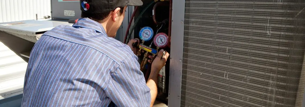 HVAC technician servicing a condenser unit in Locust