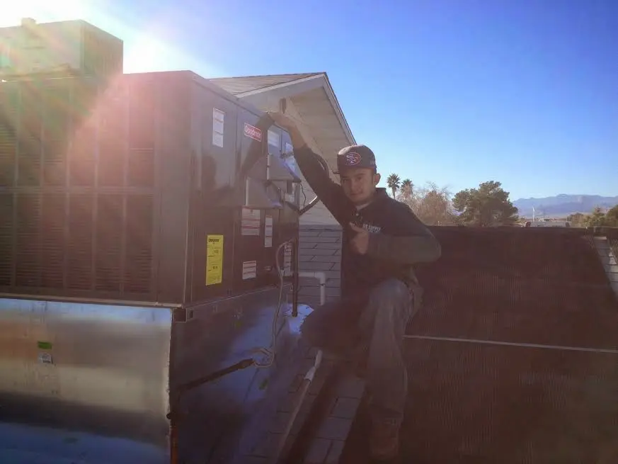 HVAC technician performing AC Tune-Up on a rooftop unit in Locust